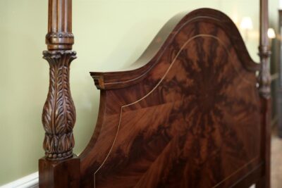 Acanthus leaf carved posters and architectural molding atop flame mahogany headboard